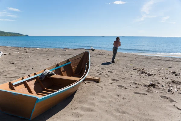 Rybář táhne těžký dřevěný člun — Stock fotografie