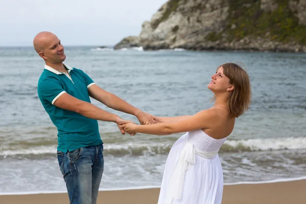 Happy pregnant woman and her husband strolling by sea. — Stock Photo, Image