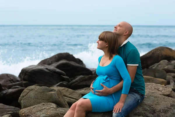 Gelukkig zwangere vrouw en haar echtgenoot aan de kust. — Stockfoto