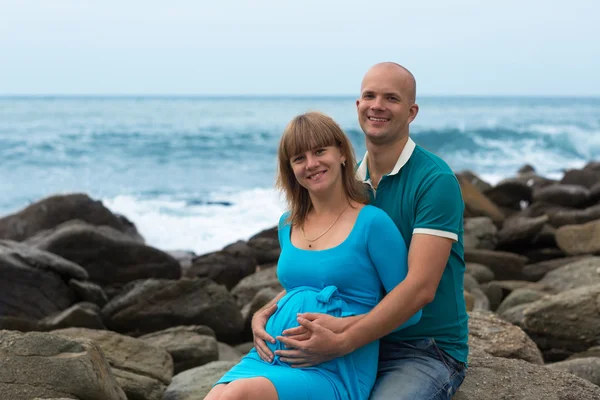 Happy pregnant woman and her husband on the coast. Stock Image