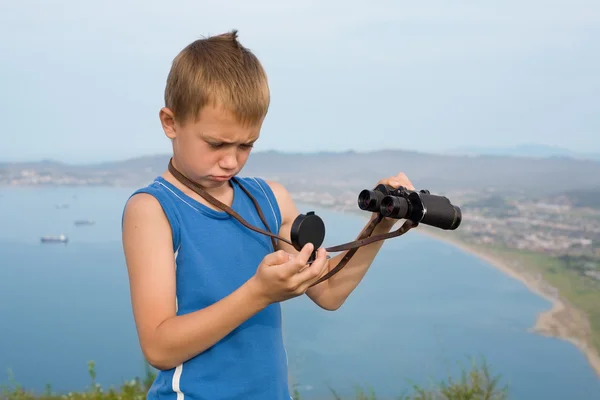 Chłopiec turysta z lornetki na szczycie góry. — Zdjęcie stockowe