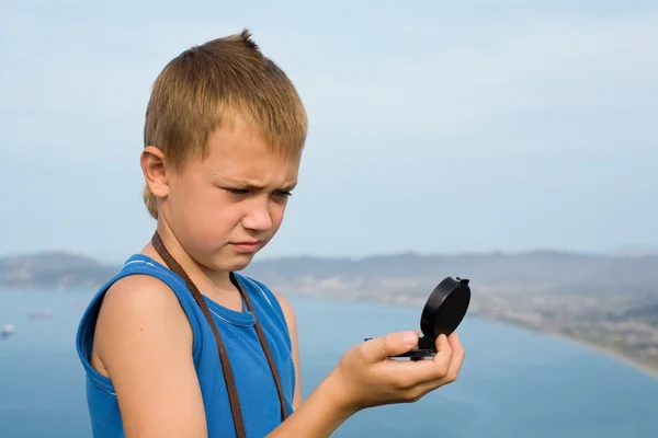 Jongen wandelaar kijken naar het kompas wordt bovenop de berg. — Stockfoto