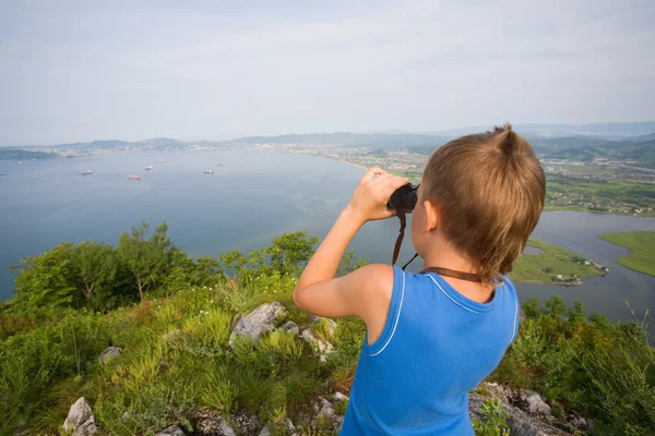 Rapaz a olhar através de binóculos do topo da montanha — Fotografia de Stock