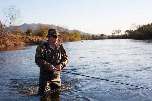 Rybář chytí lososů do řeky při západu slunce. — Stock fotografie