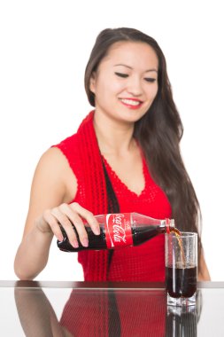 neşeli Asyalı kız bir Coca Cola cam içine dökülen.