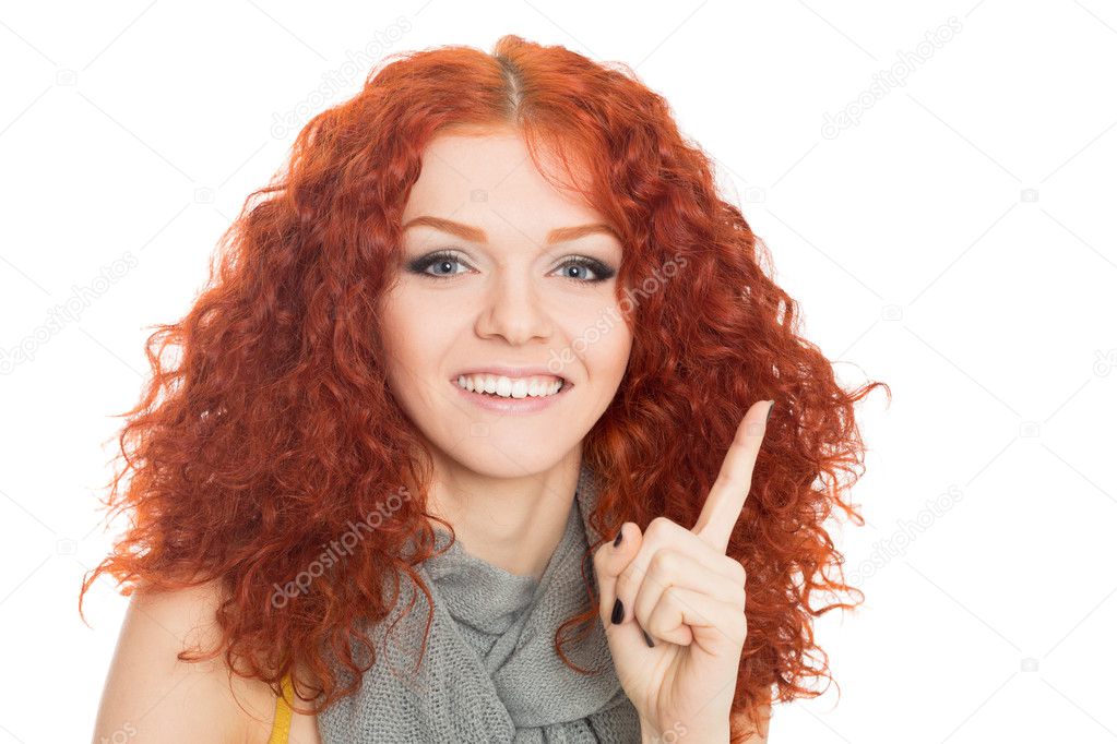 Young smiling girl points finger up.