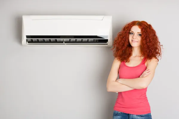 Beautiful red haired girl and air conditioner — Stock Photo, Image