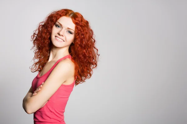 Kızıl saçlı kız arka plan gri duvar üzerinde gülümseyen — Stok fotoğraf