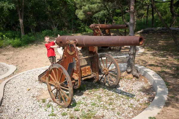 Мальчик у старой пушки на колесах — стоковое фото