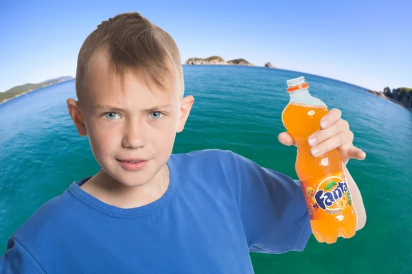 Boy with a bottle of Fanta against the sea — Stock Photo, Image