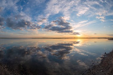Sazlıklarla kaplanmış gölün arka planına karşı kızgın bir günbatımı..