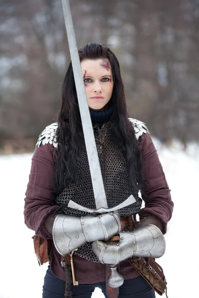 Beautiful young woman in medieval clothes holding a sword — Stock Photo, Image