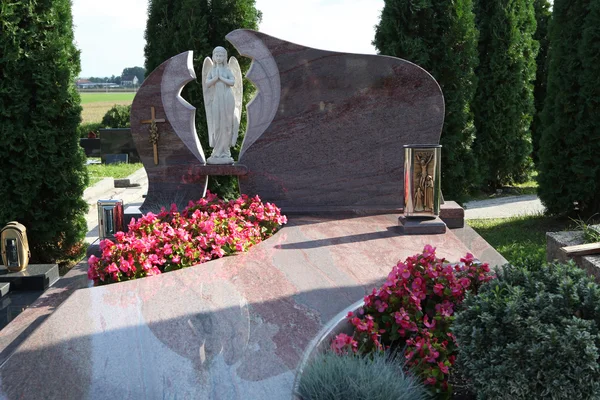 Modern tombstone with angel statue and flowers — Stock Photo, Image