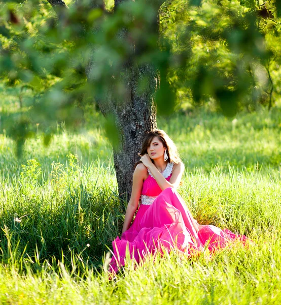 Vrouw in een lange roze jurk — Stockfoto