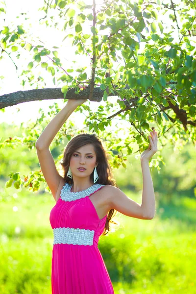 Vrouw in een lange roze jurk — Stockfoto