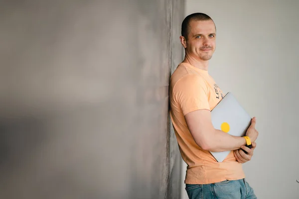 Дорослий чоловік у жовтій футболці з ноутбуком — стокове фото