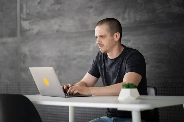 Happy man werkt op laptop in bibliotheek of coworking kantoorruimte — Stockfoto