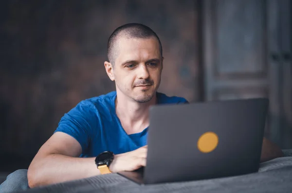 Homem adulto em camiseta azul trabalhando no laptop Fotografia De Stock