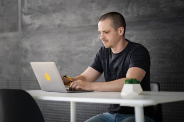 Kütüphanede dizüstü bilgisayarda çalışan mutlu bir adam ya da ofis alanı