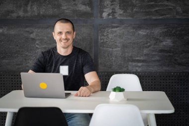 Kütüphanede dizüstü bilgisayarda çalışan mutlu bir adam ya da ofis alanı