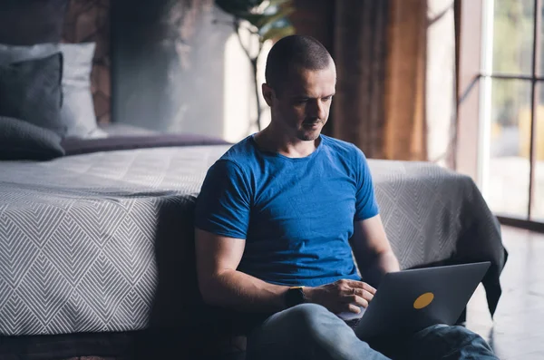 Adult man in blue t-shirt working on laptop — Photo