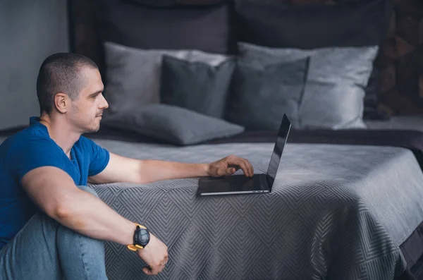 Adult man in blue t-shirt working on laptop — Stockfoto