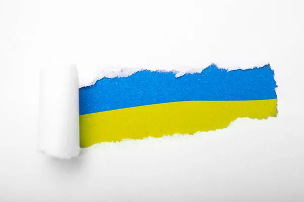 Український синій і жовтий прапор в отворі на папері — стокове фото