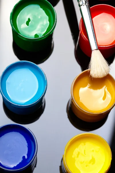 Paint buckets with paintbrush over dark background — Stock Photo, Image