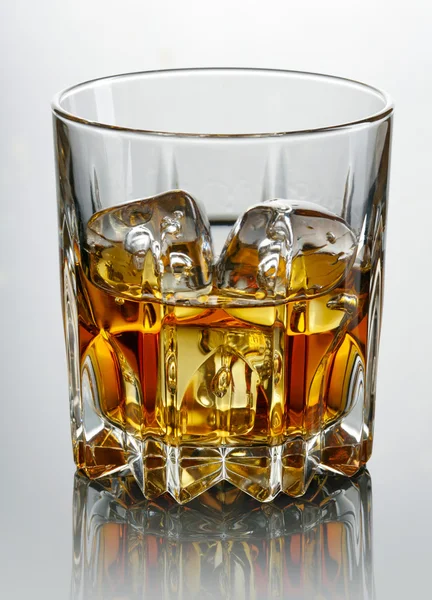 Glass of whiskey and ice over dark background — Stock Photo, Image