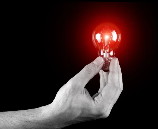 Hand holding light bulb isolated on black — Zdjęcie stockowe