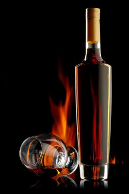 şişe ve bardak konyak alev ile koyu arka plan üzerinde