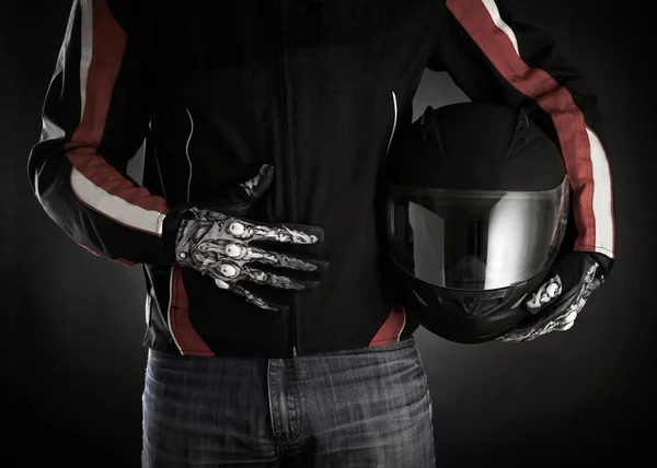 Motorcyclist with helmet in his hands. Dark background — Stock Photo, Image