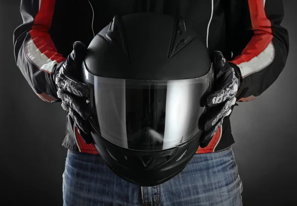 Motorcyklist med hjälm i händerna. Mörk bakgrund — Stockfoto