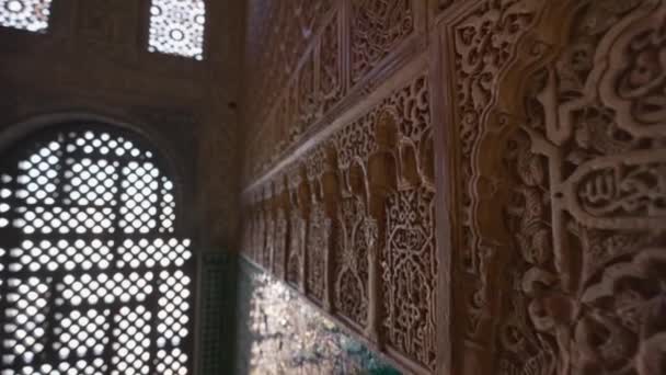 Детали стены и роскошный мавританский интерьер во дворце Альгамбра, Гранада. Камера движется к аркам окна между стенами с мавританскими орнаментами. Gimbal shot, 4K — стоковое видео