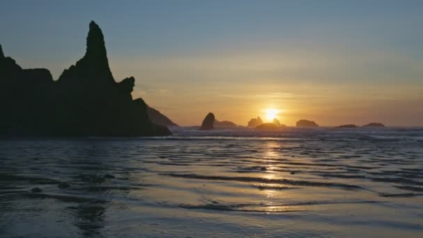 Puesta de sol en la enorme playa de arena oceánica entre piedras y rocas extrañas. Cerca de Coos Bay, Bandon, Oregon, Estados Unidos. Gimbal tiro de alta calidad, 4K — Vídeo de stock