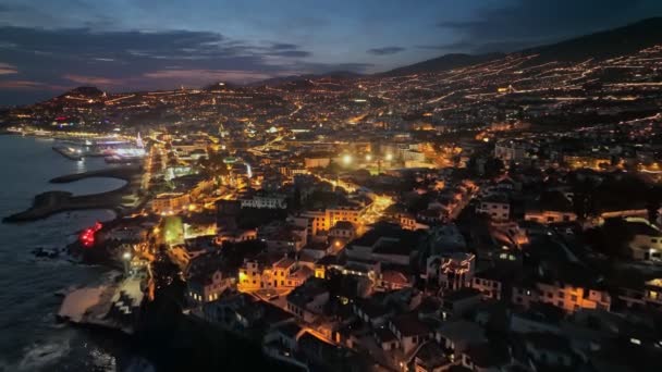 Flyger över kusten på kvällen Funchal, blå solnedgång himmel och stadsljus. Flygfoto över natten Funchal stad, Madeira, Portugal — Stockvideo