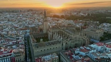 Sevilla 'nın eski kasabasında ünlü Giralda çan kulesi olan Gotik katedralin hava günbatımı manzarası. Sevilla Katedrali üzerinde uçuyor