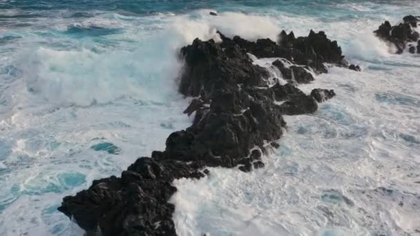 Tiro aéreo em câmara lenta de uma onda poderosa a cair sobre rochas. Mar ou oceano grande surf tempestuoso água azul-turquesa clara com textura branca espumosa. Drone aéreo disparado — Vídeo de Stock