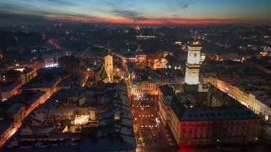 Lviv, Ukrayna 'daki tarihi şehir merkezinin muhteşem akşam manzarası. Belediye binası, şehrin ışıkları ve arka planda kızıl gün batımı.