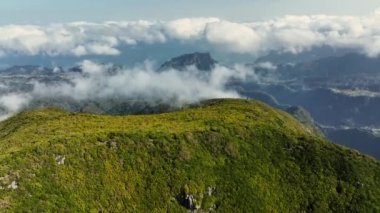 Pico Ruivo, Madeira 'daki yeşil dağların ve bulutların üzerinden uçuyor. Madeira adasının dağlarındaki sabah manzarası. UHD, 4K
