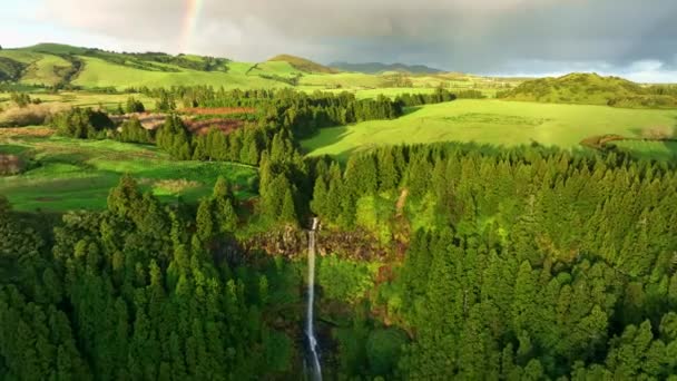 Luchtfoto van de prachtige natuur van de Azoren. Vliegen over watervallen, groene weiden en bomen. Zachte zonsondergang licht en regenboog in de lucht op Sao Miguel Island, Azoren, Portugal — Stockvideo