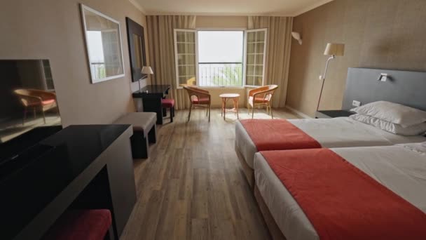 リゾートホテルの空き部屋をカメラが移動します。ベッド、テーブルと椅子2台。リラックスするには居心地の良い場所。ジンバルショット — ストック動画