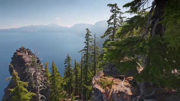 Kameny, stromy a modré jezero v národním parku Crater Lake, Oregon, USA. Gimbal výstřel na útesu s kameny, 4K. — Stock video