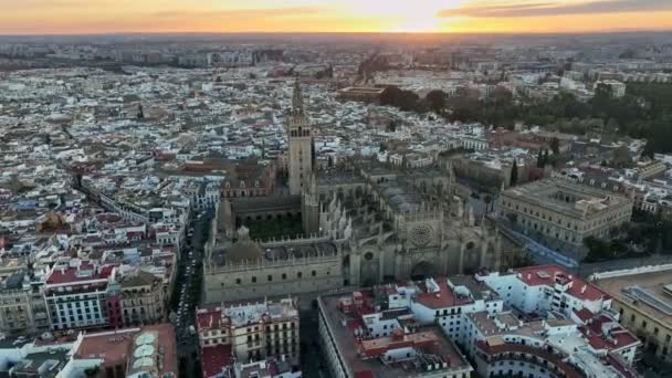 A sobrevoar a Catedral de Sevilha. Vista aérea do por do sol da catedral gótica na cidade velha de Sevilha com torre famosa do sino de Giralda — Vídeo de Stock