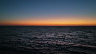 Denizin üzerinde güzel bir günbatımında uçmak. Günbatımı turuncu gökyüzü ve deniz dalgaları