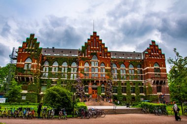 Kırmızı tuğlalı dış cephe Lund Üniversite Kütüphanesi 'nin yeşil sarmaşıklarıyla kaplıydı. İsveç 'in Lund şehrindeki ünlü tarihi bina. Mayıs 2014