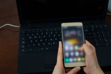 Arka planda dizüstü bilgisayarı olan bir kadının cep telefonu. Bozuk teknik cihaz için dizüstü bilgisayar desteği ya da servis arayan bir kadın. Yaşam biçimi