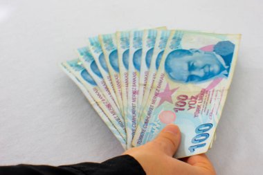 Kadın elinin elinde 100 lira değerindeki 10 banknot Türk lirası var. Lira rekor bir düşüklükle karşı karşıyayken zor zamanlarda para tasarrufu