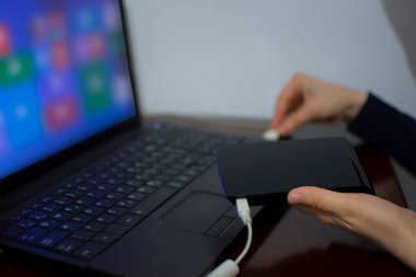 Bilgisayara kablo bağlarken harici sabit diski tutan kadın. Corona virüsü salgını yüzünden evden çalışıyor. Covid 19 ve çevrimiçi öğrenme. Yeni yaşam tarzı