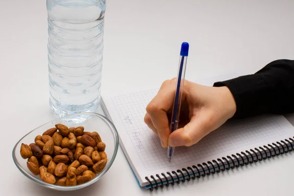 Aluno Mão Segurando Caneta Escrever Notas Caderno Tigela Vidro Avelãs — Fotografia de Stock